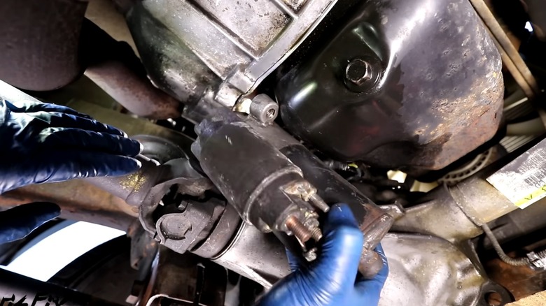 a person replacing their car's starter motor