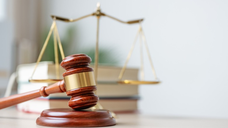 A judge's wooden gavel with scales and books in the background.