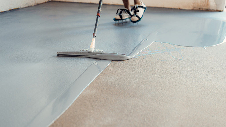 A person applying epoxy resin on concrete floor using a trowel