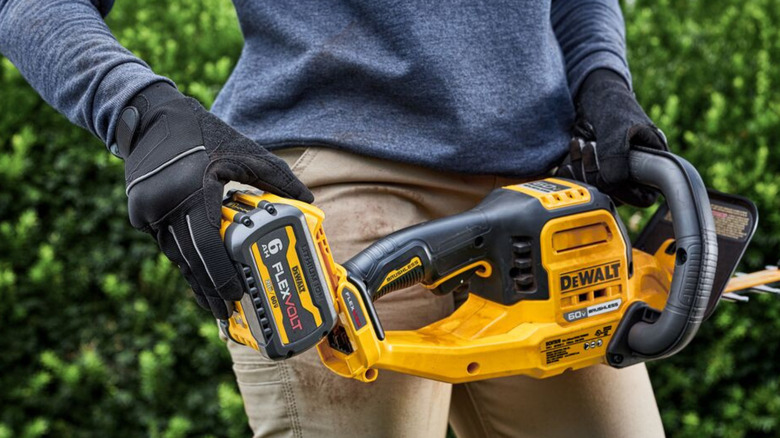 A man inserting a battery into a DeWalt chainsaw