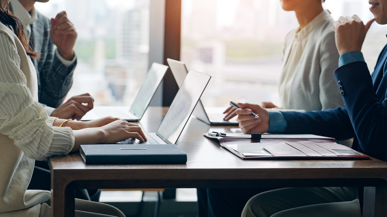 Four people work on laptops at a table