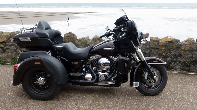 A 3-wheeler motorcycle parked next to a beach.