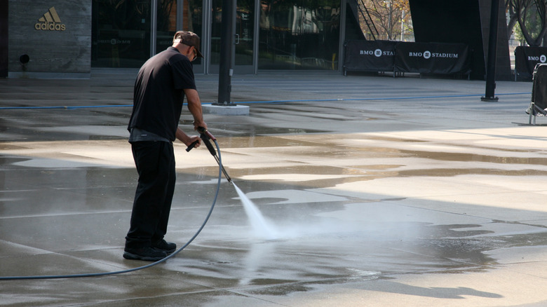 Worker using a Landa hot water pressure washer to clean paving