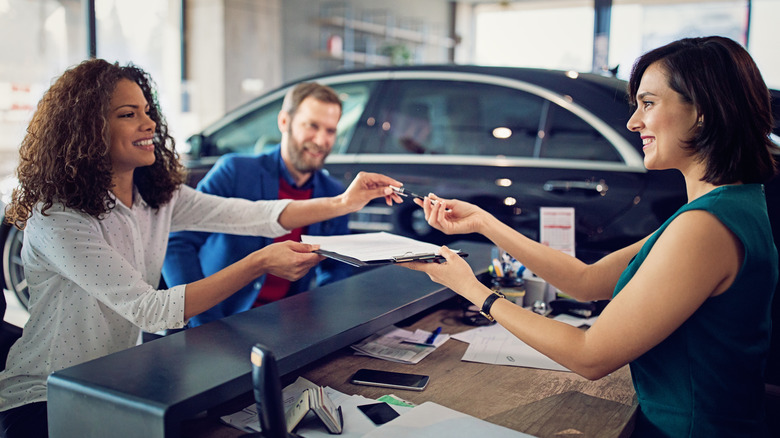 Couple signing paperwork at car dealership