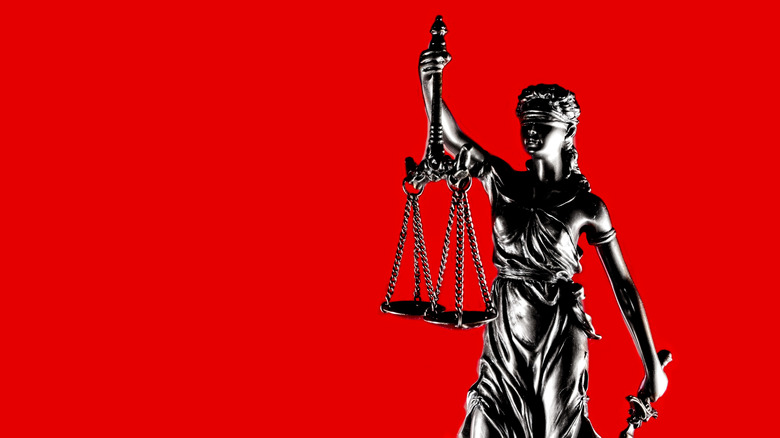 A statue of Justice against a red background.