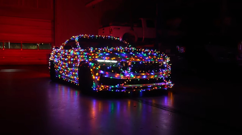 Ford Mustang wrapped in thousands of colorful Christmas lights.