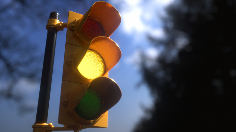Yellow traffic signal light on with blue sky in background