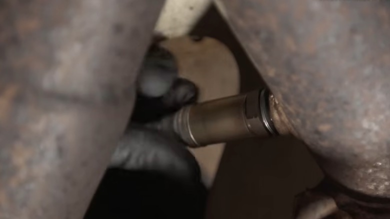 A person installing a new o2 sensor on their exhaust pipe