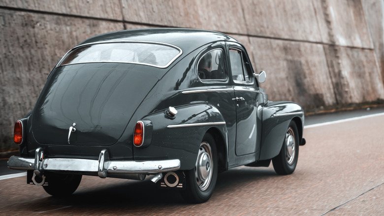 Classic Volvo PV544 driving on highway, rear-right three-quarter view