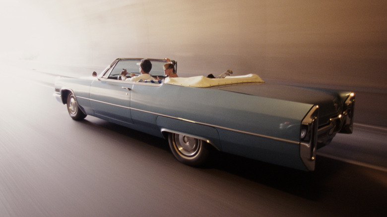 1965-1966 Cadillac Eldorado convertible with top down driving down road, left-side view