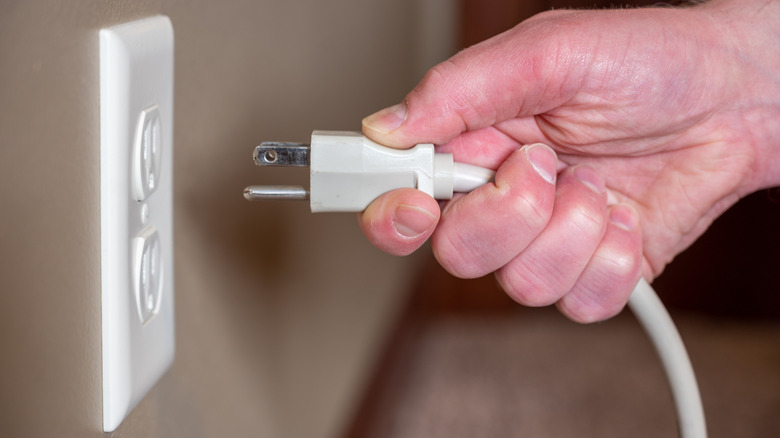 Persong plugging three prong plug into electrical outlet
