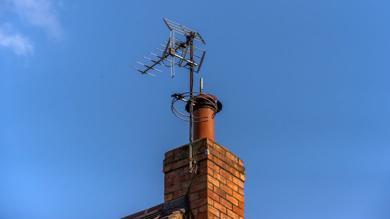 A TV antenna on top of a brick home