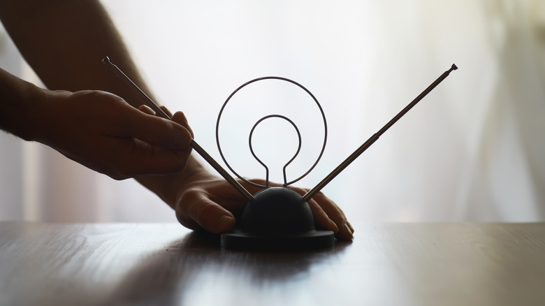 Hands adjusting a vintage TV antenna on a wooden table