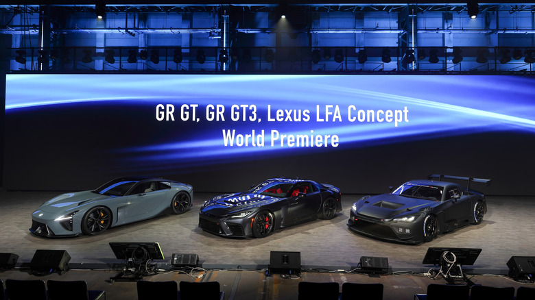 Lexus LFA, Toyota GR GT, and GR GT3 concept cars on stage, front 3/4 view, World Premiere screen behind them