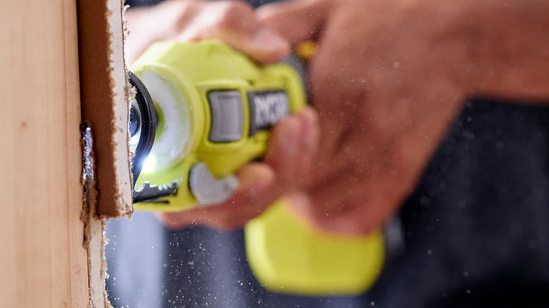 Person uses Ryobi's 18V Cut-Out Tool on wood