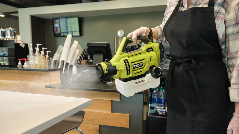 woman cleaning coffee shop with sprayer