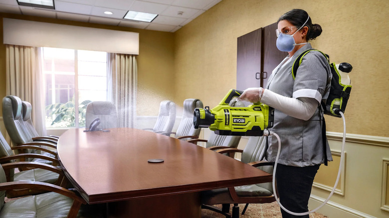 woman cleaning conference room with sprayer