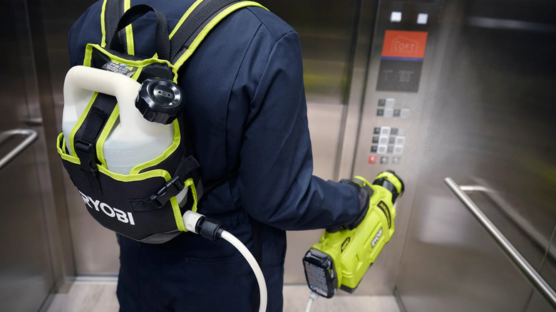 man cleaning elevator with sprayer