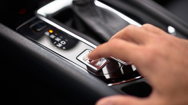 A driver selecting sport mode via switch.