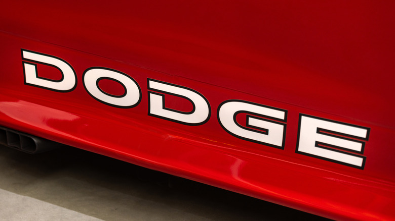A white Dodge logo on a red paint car rear