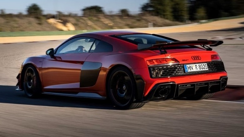 Rear 3/4 shot of a second-gen Audi R8 driving on a road with trees in the background