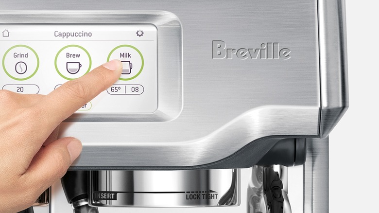 Hand touching display on Breville Barista Touch espresso machine