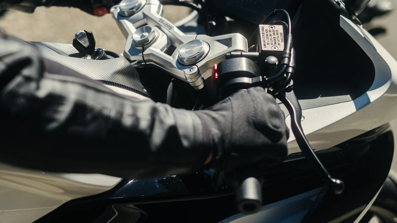 Closeup of a person grippping CFMoto 300SS handlebars