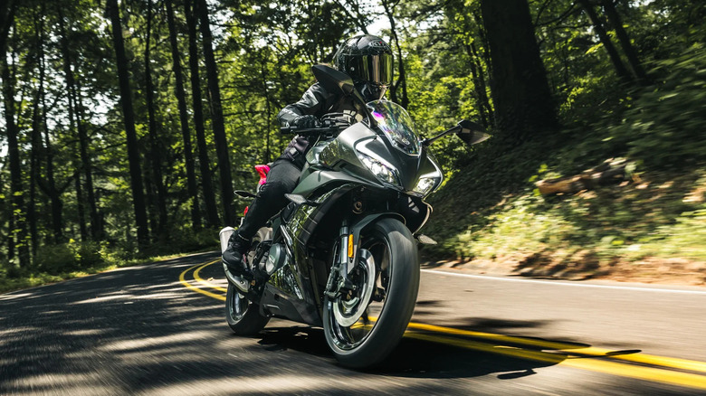 A person riding a CFMoto 300SS on a forest road
