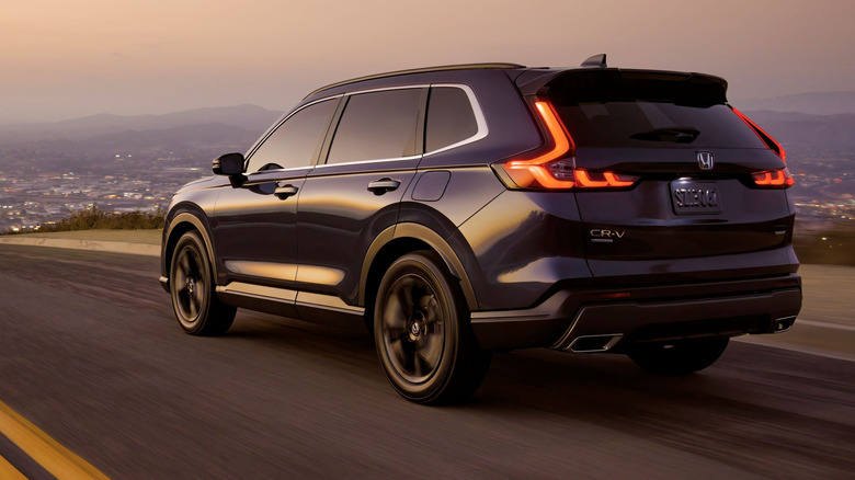 Rear 3/4 view of the 2023 Honda CR-V Sport Touring in dark blue on the move
