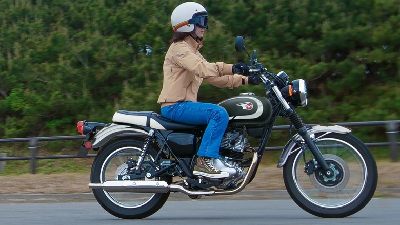 Riding the Kawasaki W230 on a tree-lined street.