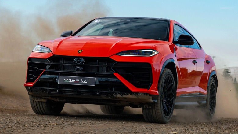 a Lamborghini Urus driving on a dusty trail