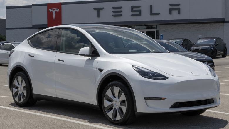 A white Tesla Model Y outside a dealership.