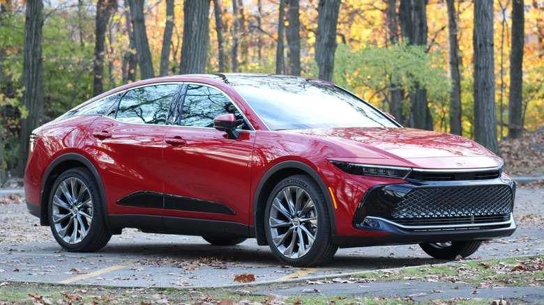 A red Toyota Crown parked in front of trees.