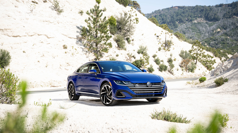 A blue Volkswagen Arteon on a mountain road, front 3/4 view
