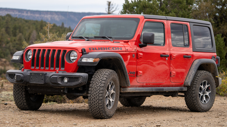 A red Jeep Wrangler Rubicon parked on a dirt path.