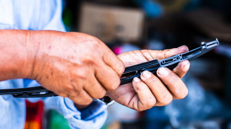 A person holding a windshield wiper blade.