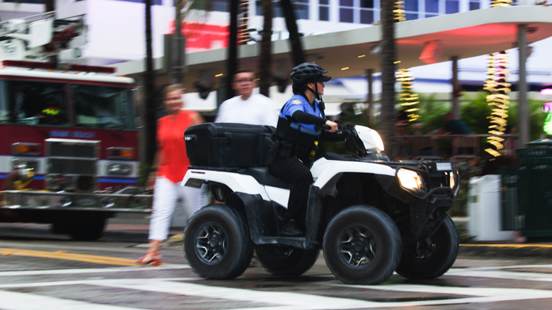A police officer on a quad bike patrols the crowds gathered for the annual Urban Beach Week celebrations on Ocean Drive in South Beach during a rainy Memorial Day Weekend.