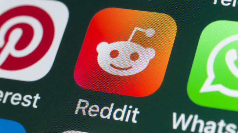 A close-up of the Pinterest, Reddit, and Whatsapp apps on a smatphone screen.