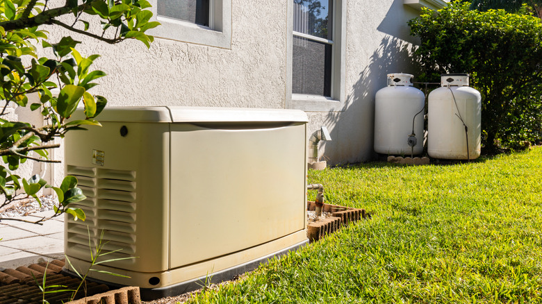A close up of two propane tanks and a generator in a backyard