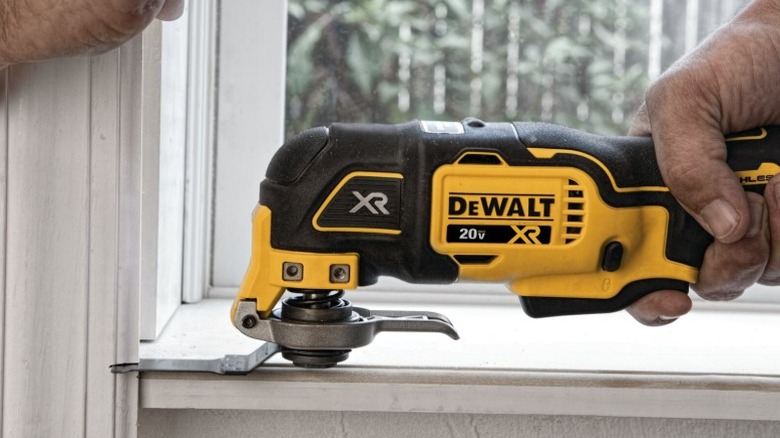 Person using DeWalt Oscillating Multi-Tool to cut window framing