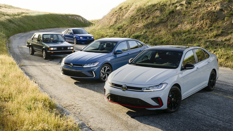 Volkswagen Jetta generations parked on mountain road.