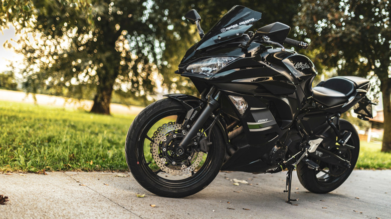 A black kawasaki ninja 650 motorcycle is parked on an asphalt road