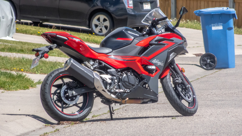 A red Kawasaki Ninja 500 motorcycle is parked on the side of a road
