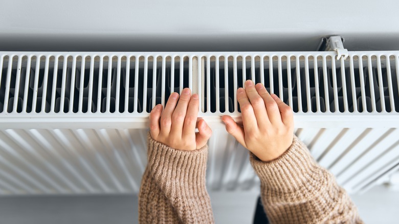 Woman warming her hands on a radiator