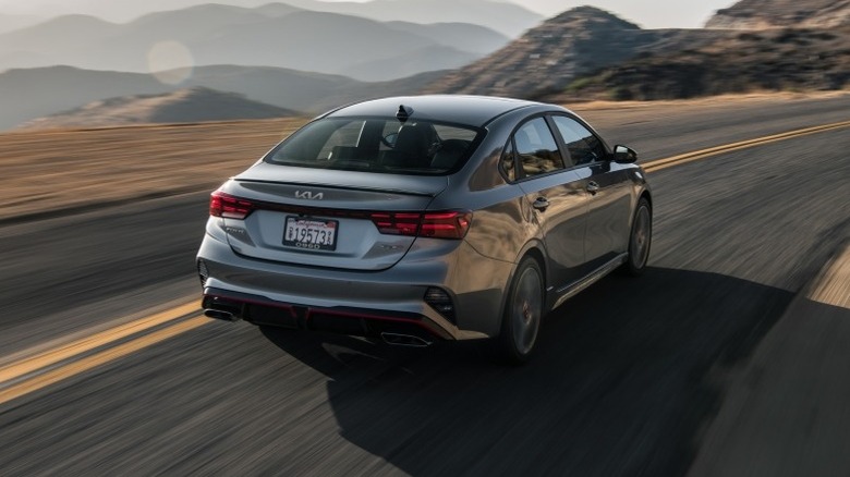 2024 Kia Forte driving on winding road with mountains in background