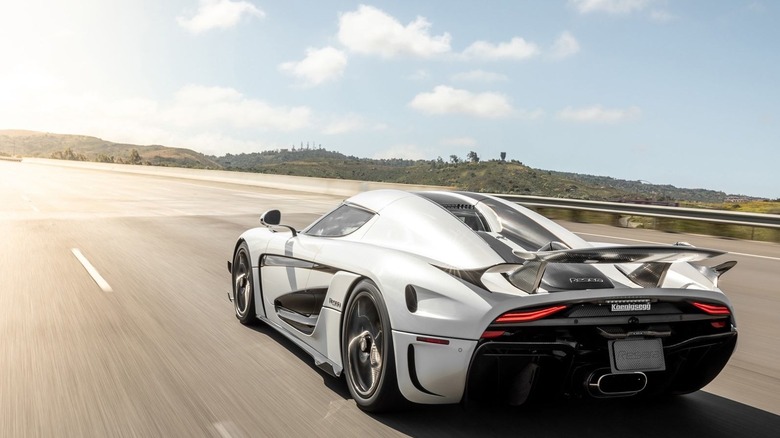 Koenigsegg Regera driving at-speed on highway, rear-left view