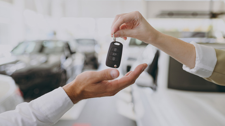 Dealer hands over key at car dealership