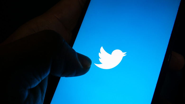 Thumb tapping Twitter logo smartphone