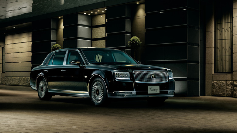 The current Toyota Century sedan outside a luxury building, front 3/4 view