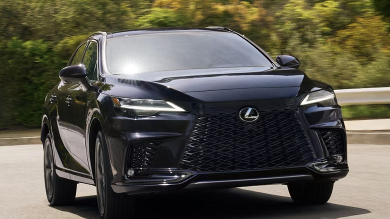front view of black Lexus RX on tree-lined highway